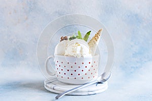 Delicious homemade cream ice cream with nuts, waffle cone and mint in a porcelain mugÂ 